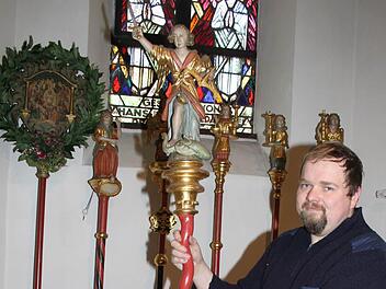 Mesner Andreas Dremer - im Bild mit dem heiligen Michael - hat es sich zur Aufgabe gemacht, die Zunftstäbe sanieren zu lassen. Foto: Sopnja Adam