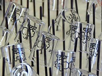 Kleine, individuell bedruckte Schnapsgläschen trocknen nach dem Druck auf einem Nagelbrett ab, ehe sie nochmals gebrannt werden.