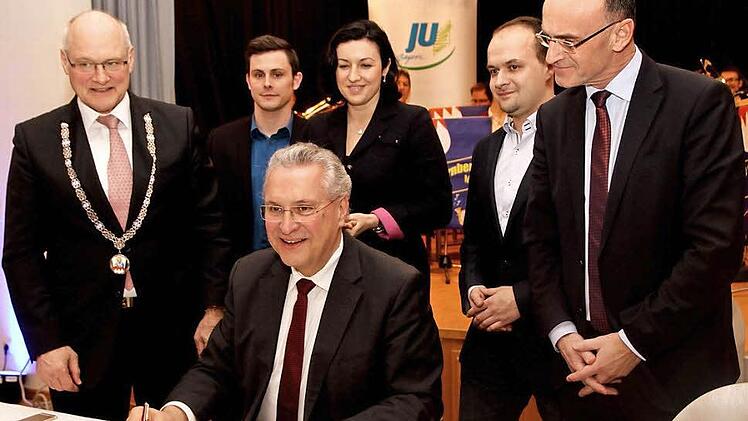 Minister Joachim Herrmann beim Eintrag ins "Goldene Buch" der Stadt Hofheim mit (von links) Bürgermeister Wolfgang Borst, JU-Vorsitzendem Felix Hein, Staatssekretärin Dorothee Bär, JU-Kreisvorsitzendem Fabian Weber und Landrat Wilhelm Schneider. Foto: Geiling