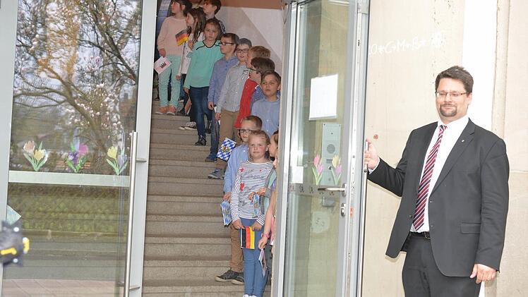 Stefan Wicklein öffnet die Tür zur Grundschule. Dahinter stehen Kinder Spalier und begrüßten Gauck,