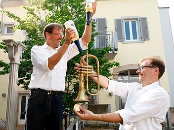 Alexander und Jochen Bähr, posieren mit ihren beiden Leidenschaften: alkoholfreiem Wein und Musik, für den Online-Auftritt ihres Familienbetriebs Bähr Pfalztraube GmbH.