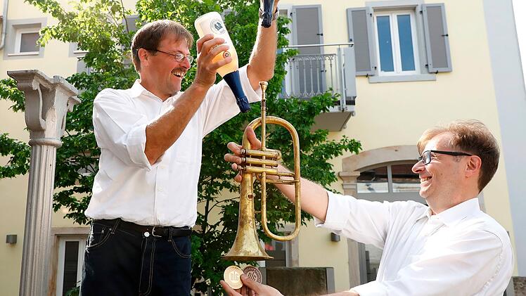 Alexander und Jochen Bähr, posieren mit ihren beiden Leidenschaften: alkoholfreiem Wein und Musik, für den Online-Auftritt ihres Familienbetriebs Bähr Pfalztraube GmbH.