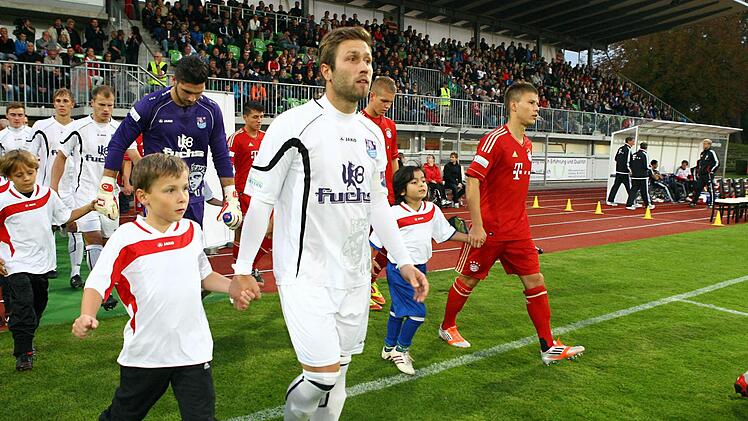 Die beiden Mannschaften betreten das Spielfeld. Vorne im wei&szlig;en Trikot der Bamberger Florian Pickel.