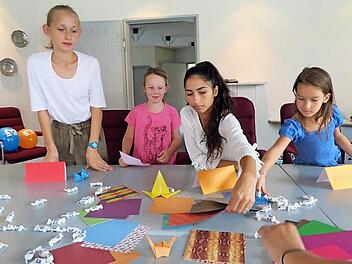 Bank-Auszubildende Yasmin ( 3. von links) unterstützt die jungen Papierkünstlerinnen. Foto: Monika Schütz