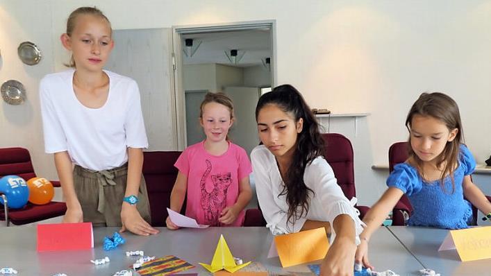 Bank-Auszubildende Yasmin ( 3. von links) unterstützt die jungen Papierkünstlerinnen. Foto: Monika Schütz