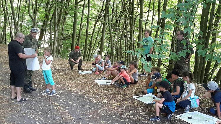Die richtige Handhabung von Karte und Kompass vermittelten den Kindern Karl Veit von der Reservistenkameradschaft und Stefan Kießner von der Bundeswehr (beide links im Bild).  Foto: Rolf Pralle
