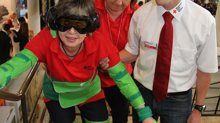 Wo auch immer Marion Hohlweg (53) mit ihrem Altersanzug auftauchte, sorgte sie für Nachfragen und Furore. Marion Hohlweg ist selbst im dritten Lehrjahr und absolviert beim BRK Bayreuth im dritten Lehrjahr die Ausbildung zur Altenpflegefachkraft. Edith Thomas assistiert ihr bei ihrem Gang als 91jährige durchs Getümmel - und Tobias Korn versucht Jugendliche für die Ausbildung für Notfallsanisanitäter zu begeistern. Derzeit ist gerade der erste Jahrgang anden Start gegangen Foto: Sonja Adam