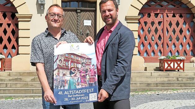 Markus Alin und B&uuml;rgermeister Mario Sch&ouml;nwald (rechts) stellen das offizielle Programm f&uuml;r das Altstadtfest in Bad Staffelstein vor.