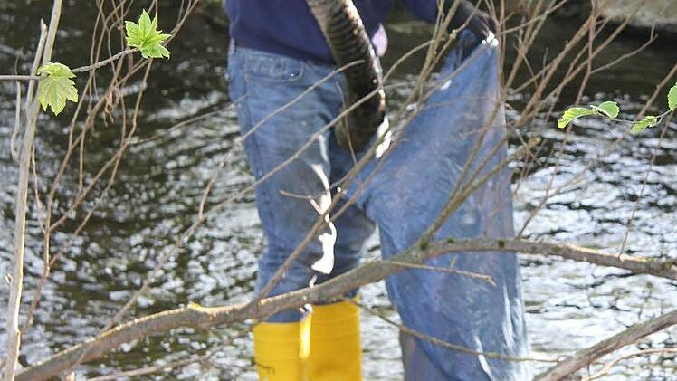 Christian Heiß sammelt Baumaterial im Bach auf.
