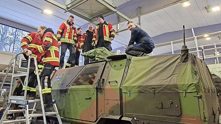 Die Feuerwehrleute schauen sich die Fahrzeuge an.