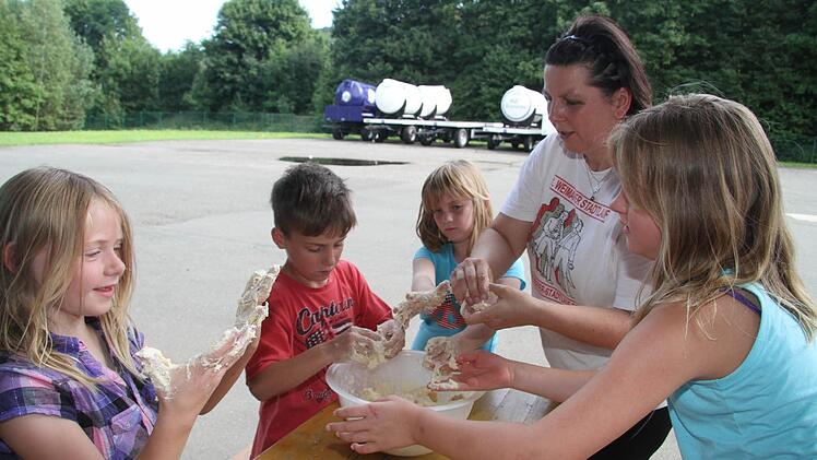 Während der Ofen vorheizt, kneten die Kids gemeinsam mit Uschi Prawitz den Pizzateig - eine klebrige Angelegenheit.