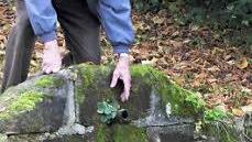 Georg Berold beugt sich über das Rohr, aus dem normalerweise das Wasser in den Teich fließt.