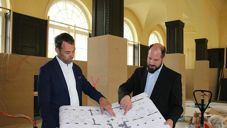 Architekt Roland Breunig (von links) und Timo Tully, Leiter des Gästeservices bei der Staatsbad GmbH, stimmen Details auf dem Plan ab. Im Hintergrund der zum Schutz der Täfelung verkleidete Saal. Fotos: Ralf Ruppert