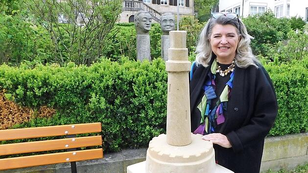 Laura Krainz-Leupoldt im Skulpturengarten vor dem Sandsteinw&uuml;rfel im Skulpturengarten, auf dem ihr Konterfei jetzt verewigt ist.