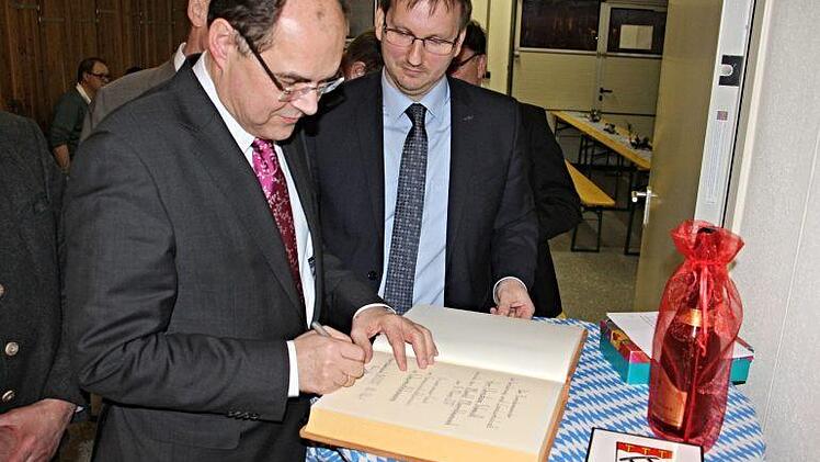 Christian Schmidt, Bundesminister für Landwirtschaft und Ernährung (links, oberes Foto), trägt sich unter den Augen von Bürgermeister Wolfram Thein in das Goldene Buch der Marktgemeinde Maroldsweisach ein.