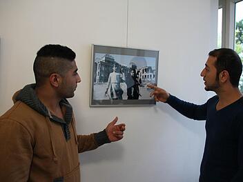 Azhand Kabeer Nahim (rechts) erklärt seinem Freund Omidreza Fayzeyan, weshalb dieses Bild trotz der Zerstörungen im Hintergrund für ihn ein Hoffnungsbild ist. Foto: Heike Beudert