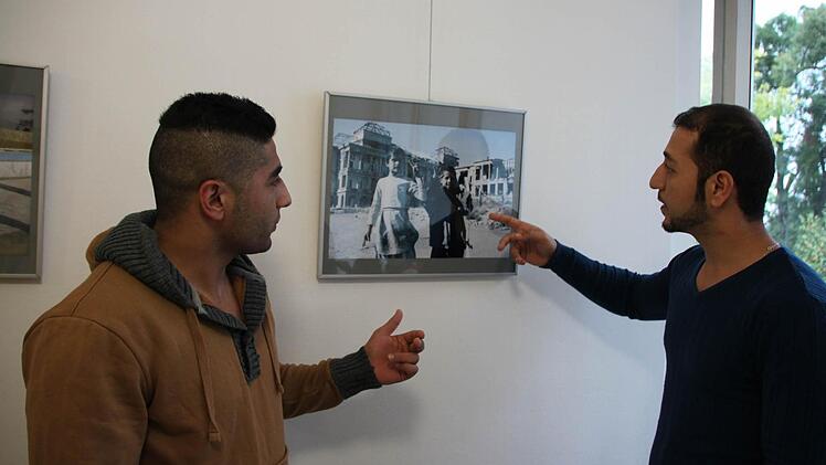 Azhand Kabeer Nahim (rechts) erklärt seinem Freund Omidreza Fayzeyan, weshalb dieses Bild trotz der Zerstörungen im Hintergrund für ihn ein Hoffnungsbild ist. Foto: Heike Beudert