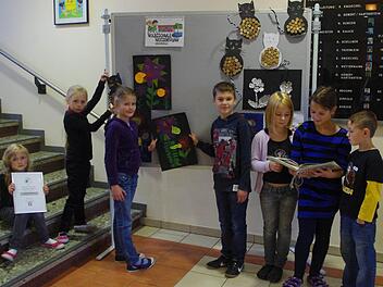 Celine, Lynn, Tina und  Nico (von links) gestalten die Ausstellungswand in der Schulaula, während Lina, Lena und Leon interessiert in der Wandzeitung zum Thema Müll schmökern. Bei den Kindern handelt es sich um die jeweiligen Klassensprecher.     Fotos: Heike Schülein