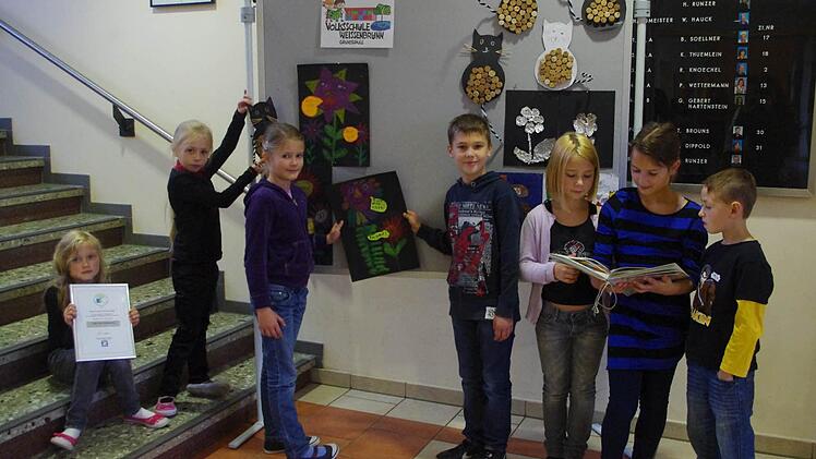 Celine, Lynn, Tina und  Nico (von links) gestalten die Ausstellungswand in der Schulaula, während Lina, Lena und Leon interessiert in der Wandzeitung zum Thema Müll schmökern. Bei den Kindern handelt es sich um die jeweiligen Klassensprecher.     Fotos: Heike Schülein