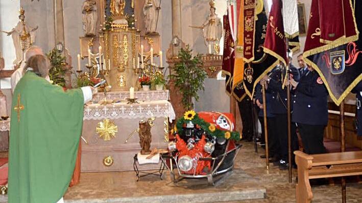 Pater Helmut Haagen segnet die in der St.Anna-Kirche im Altarraum stehende neue Tragkraftspritze 10/10 der Feuerwehr Welitsch im Beisein mehrerer Fahnenabordnungen.