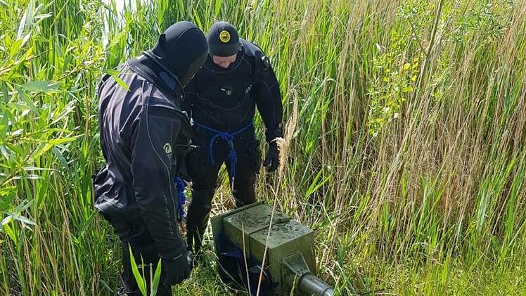 Zwei Taucher stehen vor dem abgeflexten Blitzer, der in einem See bei Leipzig lag. Diesen hatte ein 18 Jähriger dort versenkt.  Foto: Polizei Leipzig