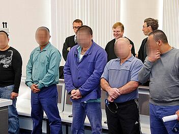 Von den neun Angeklagten passen nur fünf auf das Bild. Im Hintergrund sind drei Verteidiger zu sehen. Foto: Matthias Hoch