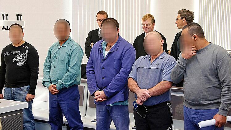 Von den neun Angeklagten passen nur fünf auf das Bild. Im Hintergrund sind drei Verteidiger zu sehen. Foto: Matthias Hoch
