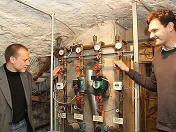 Die drei Gemeindehäuser rund um die Kirche werden noch mit Öl beheizt. Unser Bild zeigt Pfarrer Stefan Lipfert (links) mit Martin Kastner von der Energievision Frankenwald an der alten Ölheizung im "Haus der Begegnung". Foto: Alexander Hartmann