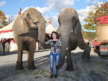 Diana Spindler vom "Circus Voyage" posiert mit zwei der Elefanten vor dem Zelt-Gehege. Foto: Thomas Heuchling