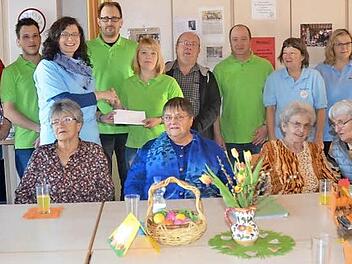 Das Glühweinbuden-Team (stehend) erfreute die Patienten von "Leben Plus" (vorne) mit einer großherzigen Spende. Hinten von links: Martin Buckreus, Markus Pohl, Heike Welscher, Oliver Schwarz, Iris Baier, Hans Büttner, Frank Hirschböck, Heidi Reichenbächer, Claudia Neubauer, Bettina Jakob, Roland Beierwaltes Foto: Hofmann