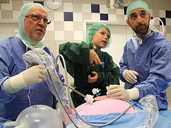 Unter der fachmännischen Anleitung der OP-Pfleger Siegfried Neubeck (links) und Jörg Heinle befördert der sechsjährige Erik aus Modlos Gummibärchen aus dem Bauch des "Patienten". Foto: Ulrike Müller