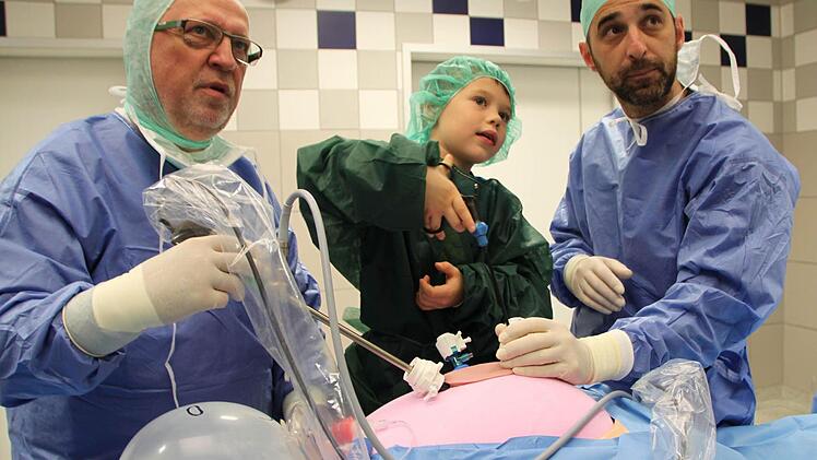 Unter der fachmännischen Anleitung der OP-Pfleger Siegfried Neubeck (links) und Jörg Heinle befördert der sechsjährige Erik aus Modlos Gummibärchen aus dem Bauch des "Patienten". Foto: Ulrike Müller