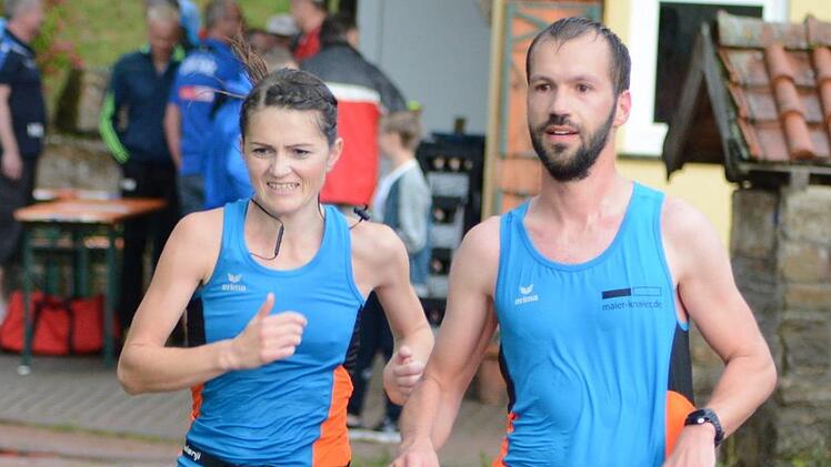 Julia Kessler (links) und Dominik Orf gehen pitschnass und durch Pfützen auf die letzte Stadionrunde.