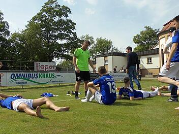 Die Jahn-Spieler (an der Bande Hayri Özdemir, liegend Genc Bajrami, in Grün Torwart Tugay Akbakla, Nr. 13 Senad Bajric und Nr. 19 Firat Güngör sowie die Trainer Michael Hutzler in Schwarz und Christian Michl mit Kappe) waren nach dem 4:0 gegen Feucht und dem Erreichen der Relegation geschafft. Foto: Daniel Ruppert