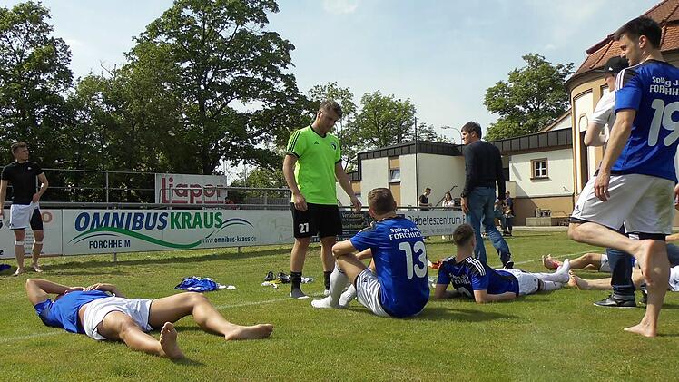 Die Jahn-Spieler (an der Bande Hayri Özdemir, liegend Genc Bajrami, in Grün Torwart Tugay Akbakla, Nr. 13 Senad Bajric und Nr. 19 Firat Güngör sowie die Trainer Michael Hutzler in Schwarz und Christian Michl mit Kappe) waren nach dem 4:0 gegen Feucht und dem Erreichen der Relegation geschafft. Foto: Daniel Ruppert