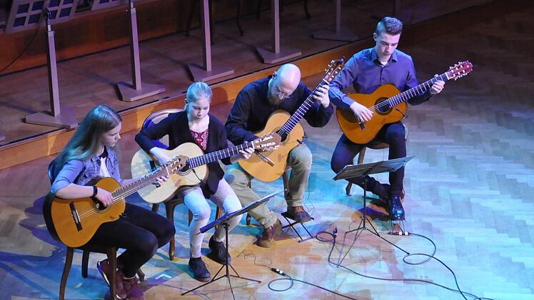 Musiklehrer Carlo Hilsdorf (Dritter von links) mit drei seiner Schüler aus der Gitarrenklasse.  Foto: Peter Klopff