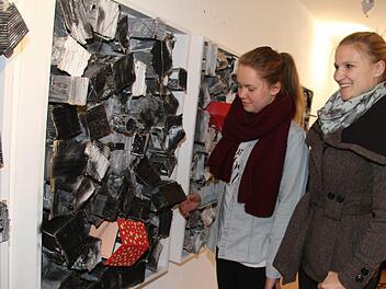 Katrin Brehm und Sophia Höreth bessern beim Aufhängen noch einmal nach. Bei diesem Kunstwerk finden den Kontrast zwischen dem getupften Haus der Hoffnung und dem trostlosen Slum gelungen. Fotos: Sonja Adam