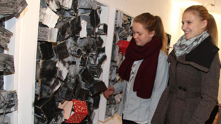 Katrin Brehm und Sophia Höreth bessern beim Aufhängen noch einmal nach. Bei diesem Kunstwerk finden den Kontrast zwischen dem getupften Haus der Hoffnung und dem trostlosen Slum gelungen. Fotos: Sonja Adam