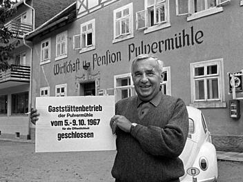 Der Vorsitzende der Gruppe 47, Hans Werner Richter, steht vor der Pulvermühle in Waischenfeld und zeigt ein Schild, das die Schließung der Gaststätte für das normale Publikum anzeigt. Archivfoto: Karl Schnörrer/dpa