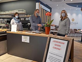 Gaby Richter und ihr Bruder Jürgen Rattmann starten heute ihre zweite Gutscheinaktion. Der Tisch steht im Café "Handgebäck", links die Geschäftsleiterin Elena Frühwald. Fotos: Bernhard Panzer