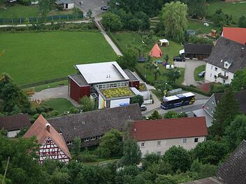 Der Kindergarten Egloffstein im jetzigen Zustand. Das rote Gebäude ist die Kita, davor ein kleiner Anbau mit begrüntem Flachdach. Links vom Anbau soll auf Anregungen des Architekten der zweigeschossige Neubau hin.  Kritiker wollen diesen weiter nach unten schieben und an den roten Bau anschließen lassen, damit oben ein Spielplatz entstehen kann. Foto: Reinhard Löwisch
