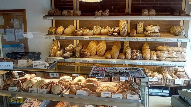 Ein B&auml;ckereigesch&auml;ft zeigt gef&uuml;llte Regale mit vielf&auml;ltigem Geb&auml;ck, Broten und Br&ouml;tchen. Im Vordergrund liegt eine Zeitung. Leider wird die B&auml;ckereikette bald schlie&szlig;en m&uuml;ssen.