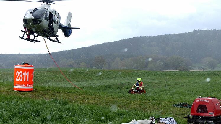 Flughelfer bringen die Last am Hubschrauber an