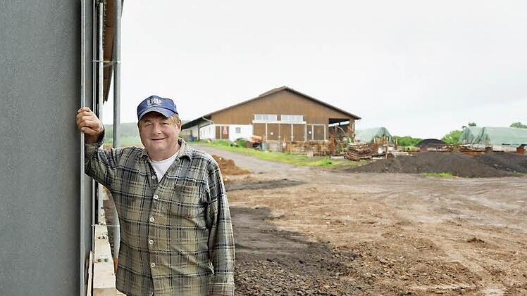 Reinhard Warmuth steht an der neuen Halle, im Hintergrund der Platz, wo das Gebäude verbrannte. Fotos: Arkadius Guzy