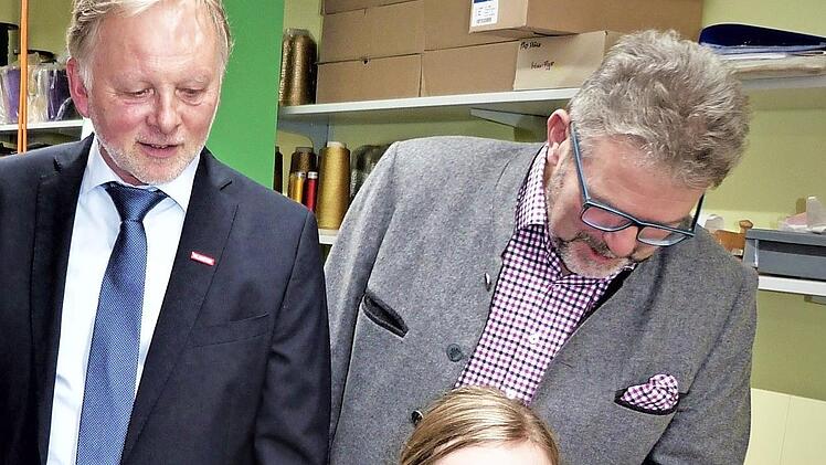 Lisa Kraus, die frisch gebackene Landessiegerin im Beruf der Textilgestalterin, an ihrem Arbeitsplatz. Dahinter Kreishandwerksmeister Günther Stenglein (links) und HWK-Präsident Thomas Zimmer. Foto: Werner Reißaus