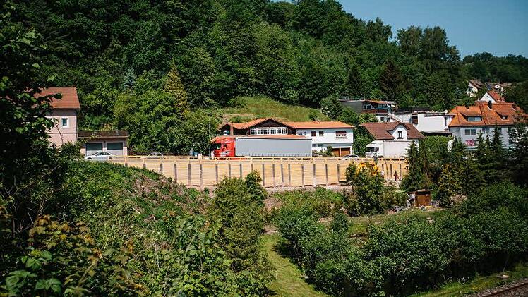 Die Holzwand ist kaum zu übersehen. Unten rechts steht das gelbe Kettenfahrzeug.