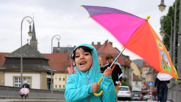 Die vierjährige Lujain hüpft auf der Ludwigsbrücke durch den Regen. Mit wasserfester Jacke und buntem Schirm ist das Mädchen perfekt für einen Spaziergang im Regen ausgerüstet.  Fotos: Kathrin Kupka-Hahn