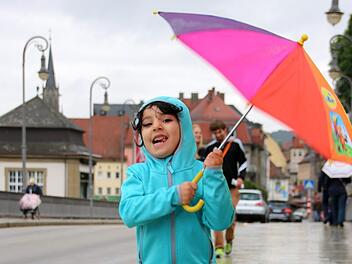 Die vierjährige Lujain hüpft auf der Ludwigsbrücke durch den Regen. Mit wasserfester Jacke und buntem Schirm ist das Mädchen perfekt für einen Spaziergang im Regen ausgerüstet.  Fotos: Kathrin Kupka-Hahn
