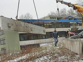 Dominik Günther steht hinter einer Betonblende, die ein Kran heruntergehoben hat. Dieses Element, so kann man hier gut sehen, war mit drei Trägern mit dem Dach verbunden. Fotos: Tobias Kindermann