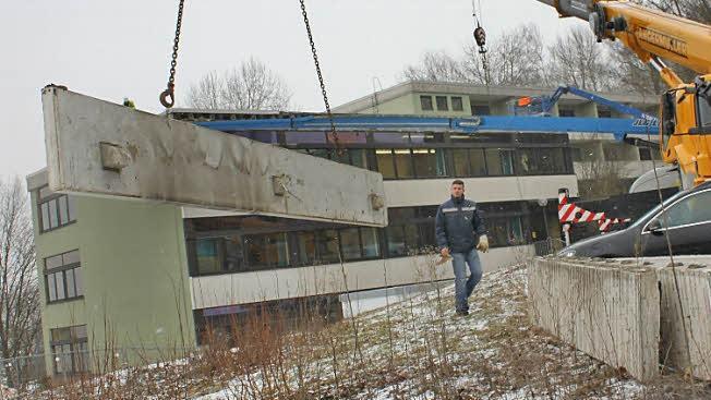 Dominik Günther steht hinter einer Betonblende, die ein Kran heruntergehoben hat. Dieses Element, so kann man hier gut sehen, war mit drei Trägern mit dem Dach verbunden. Fotos: Tobias Kindermann